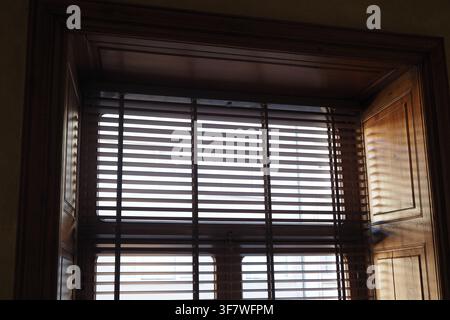 Light filtering through wooden blinds in a room Stock Photo