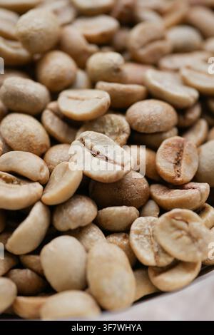 green coffee beans in various shapes and sizes on a table Stock Photo