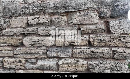 Ancient stone wall with rough texture and weathered bricks Stock Photo