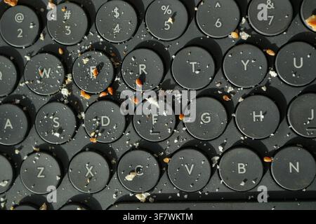 Keyboard covered in crumbs and debris at a workspace Stock Photo
