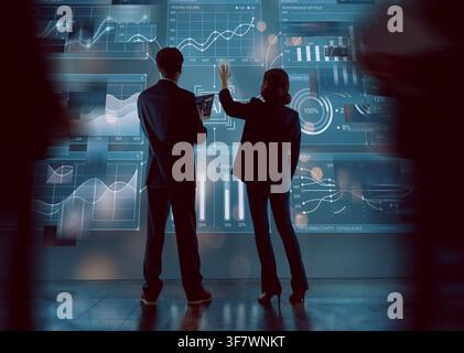 Dynamic scene of business professionals collaborating and analyzing financial data on an immersive futuristic digital screen. This image captures inno Stock Photo