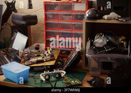 Computer hardware components lying on messy workshop desk with laptop and tools, representing electronics repair. Image suitable for IT support and hardware engineering services Stock Photo