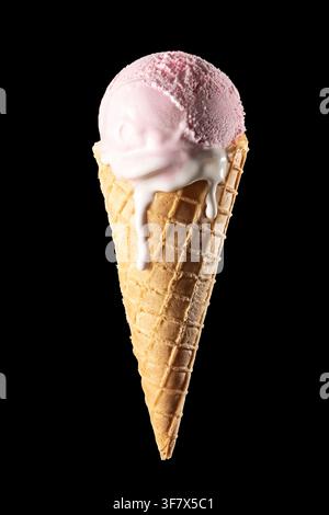 Pink strawberry ice cream scoop in waffle cone melting isolated on black background, vertical Stock Photo