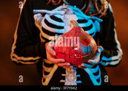 Child in Skeleton Costume Holding Glowing Jack O Lantern Stock Photo