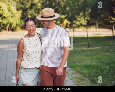 A smiling man and woman stroll side by side through a green park, enjoying each other's company. Stock Photo
