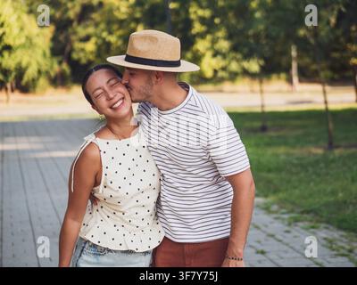 A young couple shares a playful and affectionate moment while walking together in park. Stock Photo