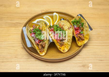 Close-up of birria-style quesatacos with cilantro, onion, lime wedges, and consommé on a slate plate. Stock Photo