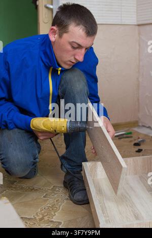 worker drills a hole when assembling furniture Stock Photo