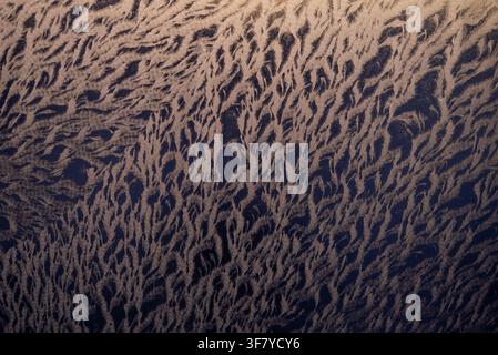 Frost patterns developing on glass, showcasing intricate ice crystals forming a beautiful, abstract texture against a dark background during cold winter weather Stock Photo