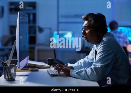 Middle Aged Man Working in it Support Center at Night Stock Photo