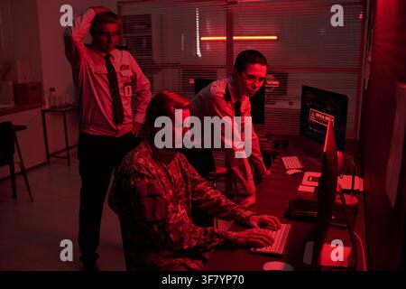 Military Officer and Security Guards Managing Cyber Attack in Control Room Stock Photo