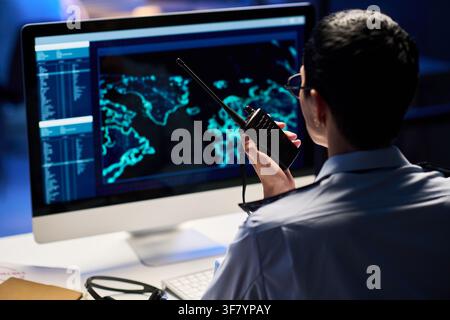 Security Officer Holding Walkie Talkie Looking at Surveillance Screen Stock Photo