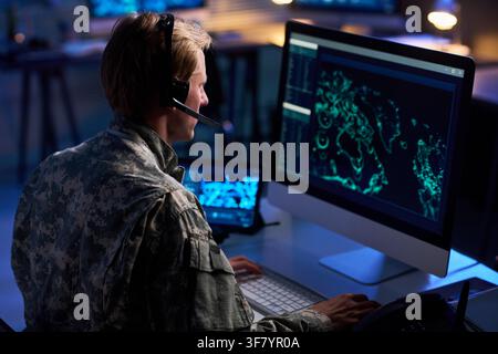 Military Officer Wearing Headset Analyzing Digital Map on Computer Screen Stock Photo