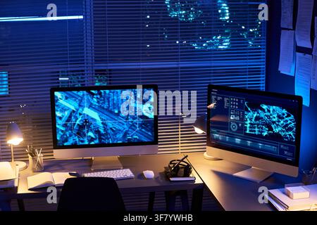 Computer Monitors Displaying Digital Maps in Dark Security Control Room Stock Photo