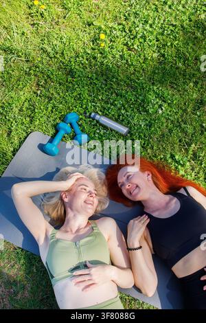 Two sporty middleaged smiling women on outdoor workout lying on the Stock Photo