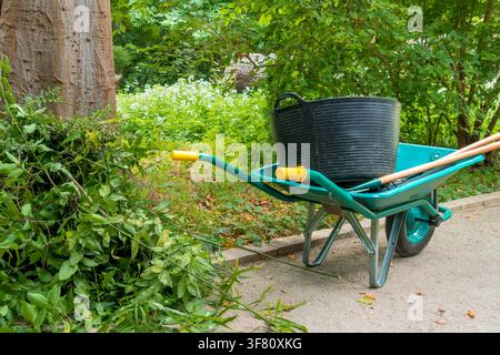 Green Garden Cart Filled with Cut Branches in a Park Stock Photo