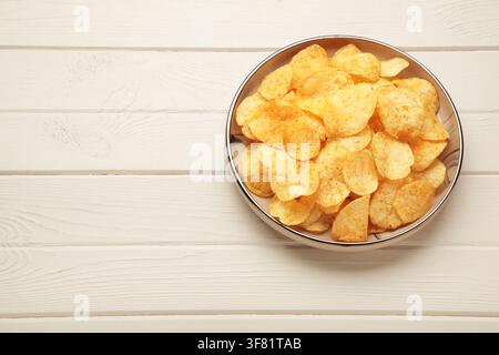 Potato chips on plate on white wooden background. Top view Stock Photo