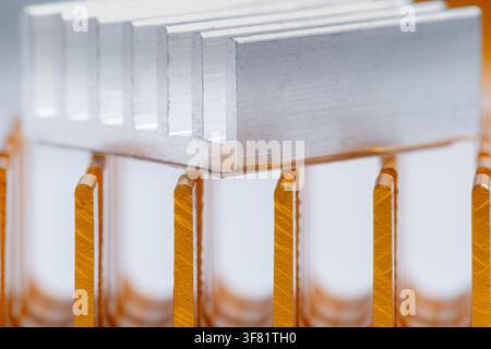 Metallic component gleams under soft light. Vertical fins stand proud, designed for heat dissipation. Precision engineering reflects modern industrial Stock Photo