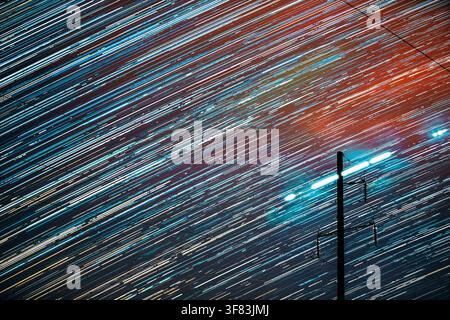 Unusual Amazing Effects In Sky. Bright Night Starry Sky Background. Trails Of Stars Rotate Above Power Line. Large Exposure. Imagination, Fantasy Stock Photo