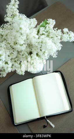 Top view of opened holy bible scripture lying near blooming white lilac bouquet on wooden table Stock Photo