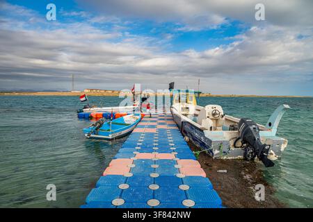 Boats docked at Arous camp in the Red Sea with cloudy sky over the water in Sudan Stock Photo