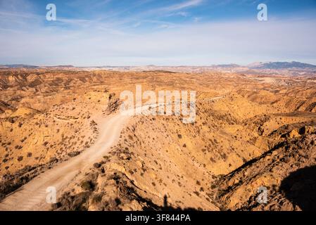 Winding road travels through dry hills and low vegetation in scenic desert landscape in Spain Stock Photo