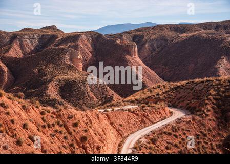 Winding dirt road through the red badlands of a semi-arid landscape in Spain's Gorafe Desert Stock Photo