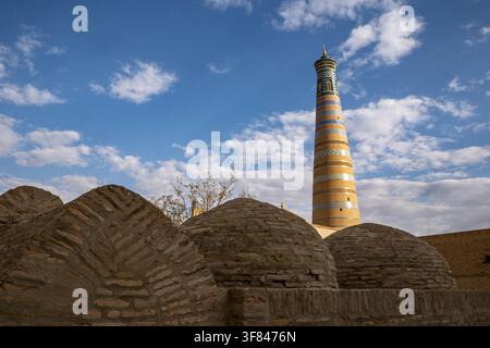 Visit to the unique minaret of Islam Khodja medersa in Khiva, Uzbekistan under blue sky and scattered clouds Stock Photo