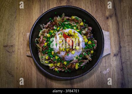 Delicious Vietnamese fried rice served with beef and vegetables on a wooden table in Vietnam Stock Photo