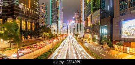 Skyscrapers glow as car trails light up the streets during dusk in Wan Chai District, Hong Kong Stock Photo