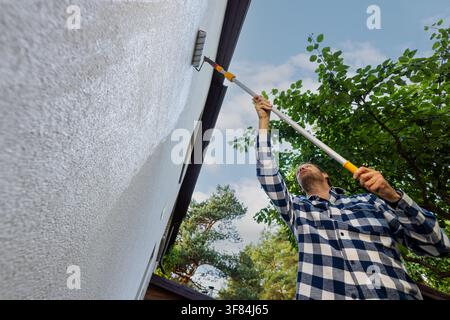 house painter restore paint on decorative plaster exterior wall with roller Stock Photo