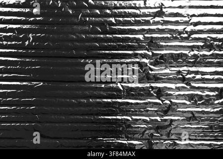 Black metallic silver foil insulation material with ridges and bubble packaging texture. Abstract dark grunge background Stock Photo