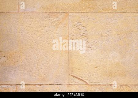 Ancient architectural wall with rectangular stone blocks. Aged mineral plaster and weathered seams. Abstract architecture background Stock Photo