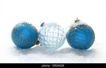 Elegant blue and ice glass Christmas ornaments resting on a soft fake snow background. Winter holiday celebration concept. Stock Photo