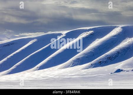 Snow covered mountain slope in Arctic landscape at Mohnbukta, bay at the western shore of Storfjorden in Sabine Land at Spitsbergen / Svalbard Stock Photo