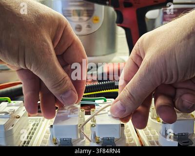 A technician works on connecting wires in a junction box during an electrical installation at home in the daytime. Stock Photo