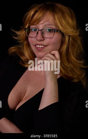 Young woman with red hair wearing glasses, smiling at the camera Stock Photo