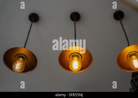 Rustic metallic pendant lamps with illuminated glass bulbs, featuring antique industrial interior design, warm illumination, and cozy atmosphere Stock Photo