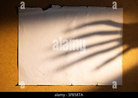 Vintage torn paper with eerie hand shadow on warm background for Halloween poster or horror flyer Stock Photo