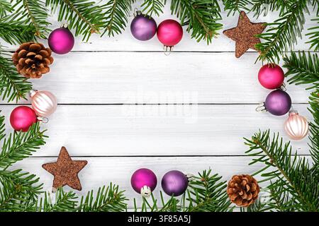 Christmas frame with Abies nordmanniana branches, colorful baubles, pine cones and glitter stars on white wood Stock Photo