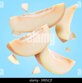 Sweet melon pieces flying in air on light blue background Stock Photo