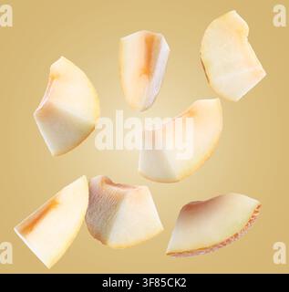 Sweet melon pieces flying in air on pastel brown background Stock Photo