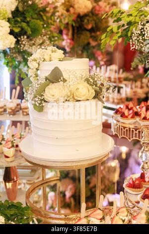 Close-up of two tier wedding cake decorated with fresh flowers on elegant reception dessert table at wedding celebration Stock Photo