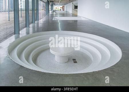 Minimalist modern interior with circular sunken seating, white tiled surfaces and polished concrete floor. Contemporary architecture, geometric design Stock Photo