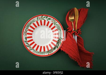 Christmas Table Setting with Festive Plates and Red Napkin on Green Background Stock Photo
