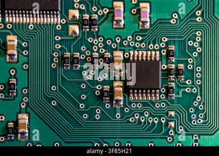 Intricate microchips and green tracks of a modern printed circuit board in close-up, reflecting advanced microelectronics. Stock Photo