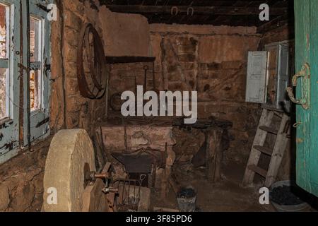 Interior of an ancient blacksmith's forge in Territorio Artlanza, featuring rustic tools, stone walls, and a traditional grinding wheel, Spain. Stock Photo