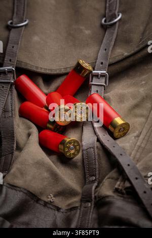 Red 12 gauge shotgun shells lying on a vintage canvas hunting backpack. Stock Photo