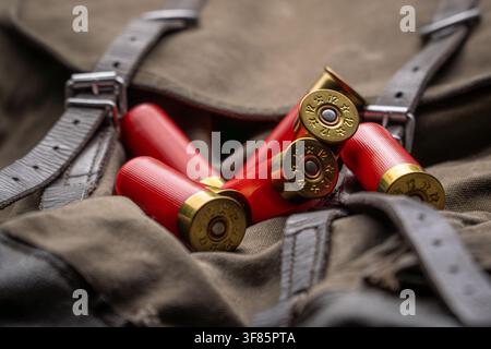 Red 12 gauge shotgun shells lying on a vintage canvas hunting backpack. Stock Photo