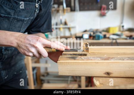 Wooden board preparation process for restoration in carpentry workshop, master chisels wood surface. Stock Photo